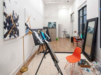 a room with paintings on the wall and a tripod in the middle